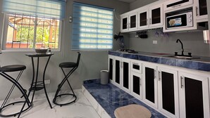 A kitchen with white cabinets, a marble countertop, and a small dining area with two chairs.