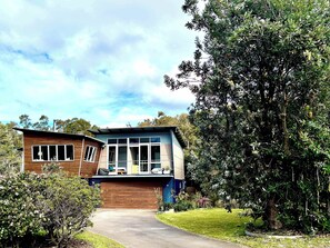 A modern two-story house with a garage, surrounded by lush greenery and trees. - Murramarang Haven at Bawley Point (Bawley Point)