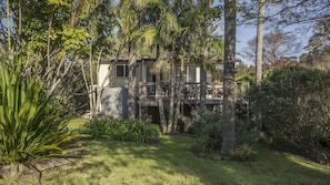 Ein Haus mit Terrasse, umgeben von üppiger Vegetation und Bäumen.