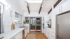 Una cocina moderna con armarios blancos, un refrigerador de acero inoxidable y una encimera de madera.