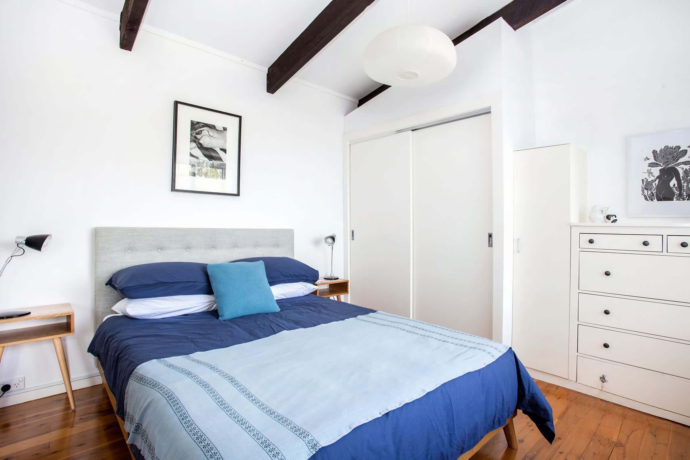 A bedroom with a bed, bedside tables, a wardrobe, and a ceiling light.