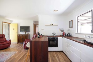 A compact kitchen with a built-in oven, a coffee maker, and a sink. - Sandy's Beach Shack at Bawley (Bawley Point)