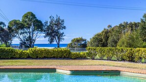 A swimming pool with clear blue water, surrounded by well-maintained hedges and trees. - Fathoms 19 at Mollymook (Mollymook Beach)