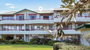 A multi-story building with a symmetrical facade, large windows, and a central entrance. - Fathoms 19 at Mollymook (Mollymook Beach)