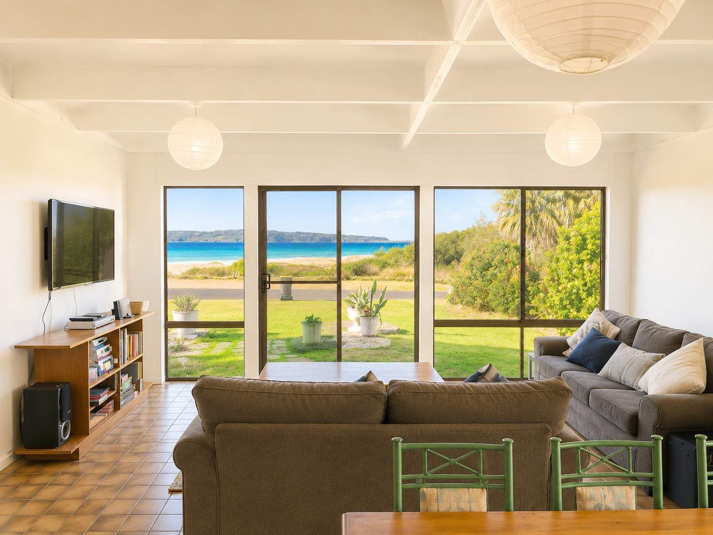 A living room with a large window, a sofa, a TV, and a bookshelf.