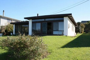 Ein modernes, zweistöckiges Haus mit großen Fenstern, einer flachen Dachkonstruktion und einem gepflegten Rasen.
