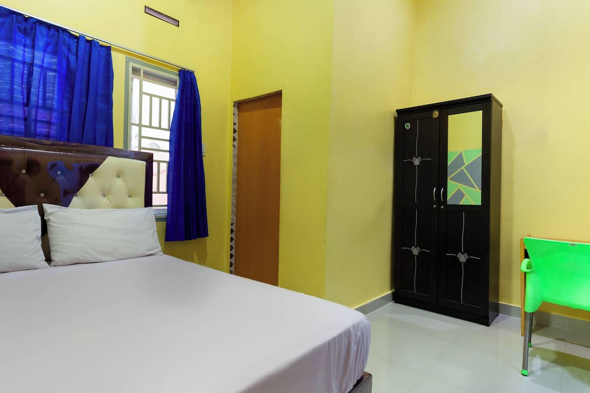 Una habitación con cama, armario, silla y ventana con cortinas.