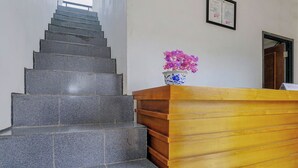 Un mostrador de recepción con un florero, un certificado enmarcado en la pared y una escalera.