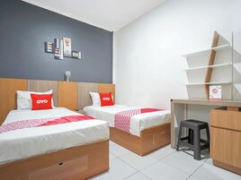 A hotel room with two beds, a desk, and a wardrobe.