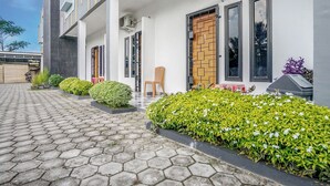 Un edificio moderno con un sendero pavimentado, una puerta de madera y una silla afuera.