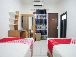 A room with two beds, a wardrobe, a desk, and a door.
