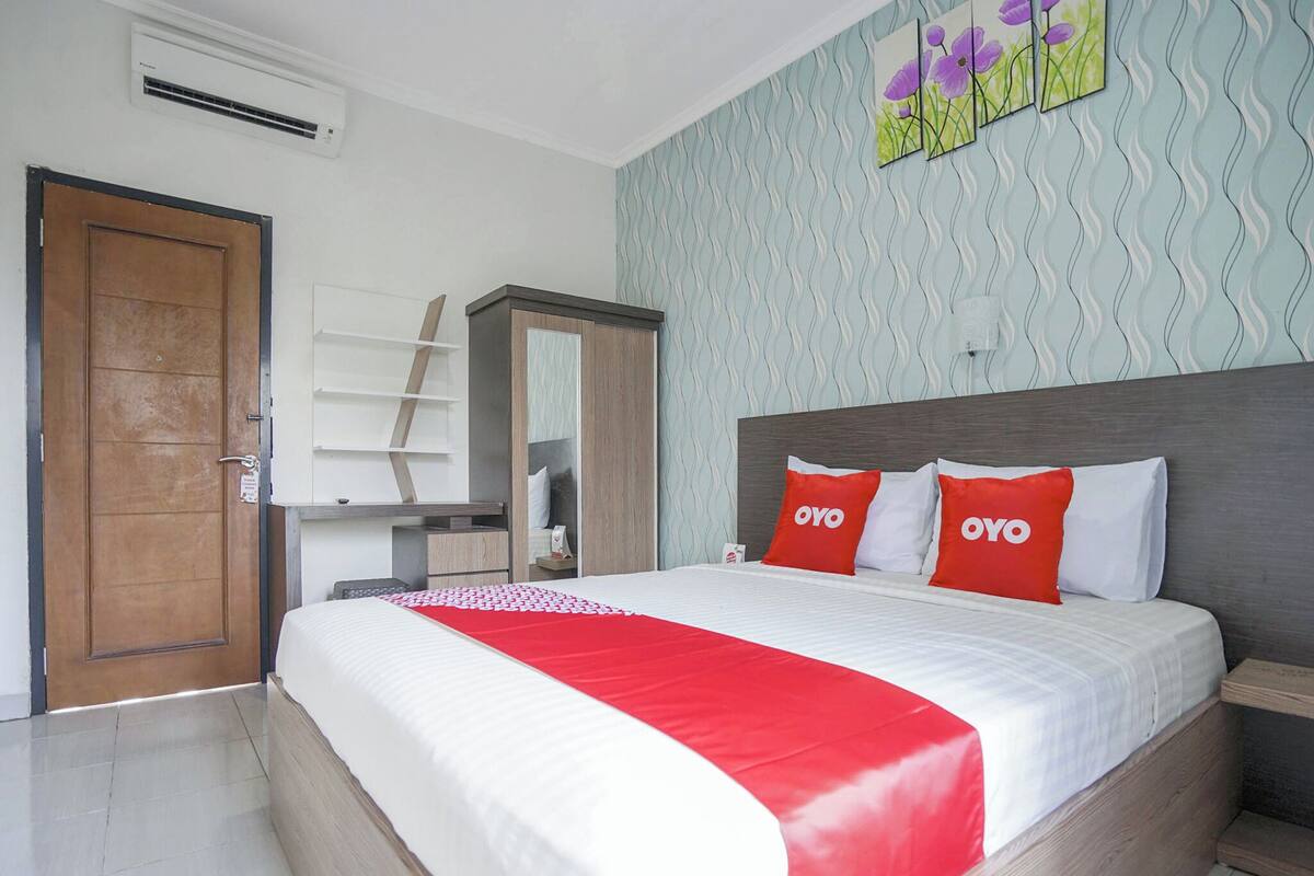 Um quarto com cama, guarda-roupa, escrivaninha e porta.