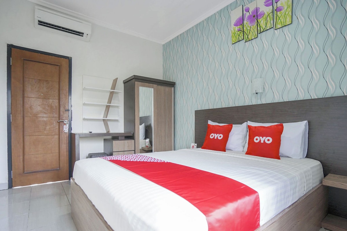 Um quarto com cama, guarda-roupa, escrivaninha e porta.