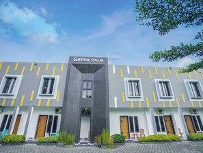 A building with the sign 'GREEN PALM' at the top, featuring a modern architectural design with a central entrance and multiple windows on each floor.
