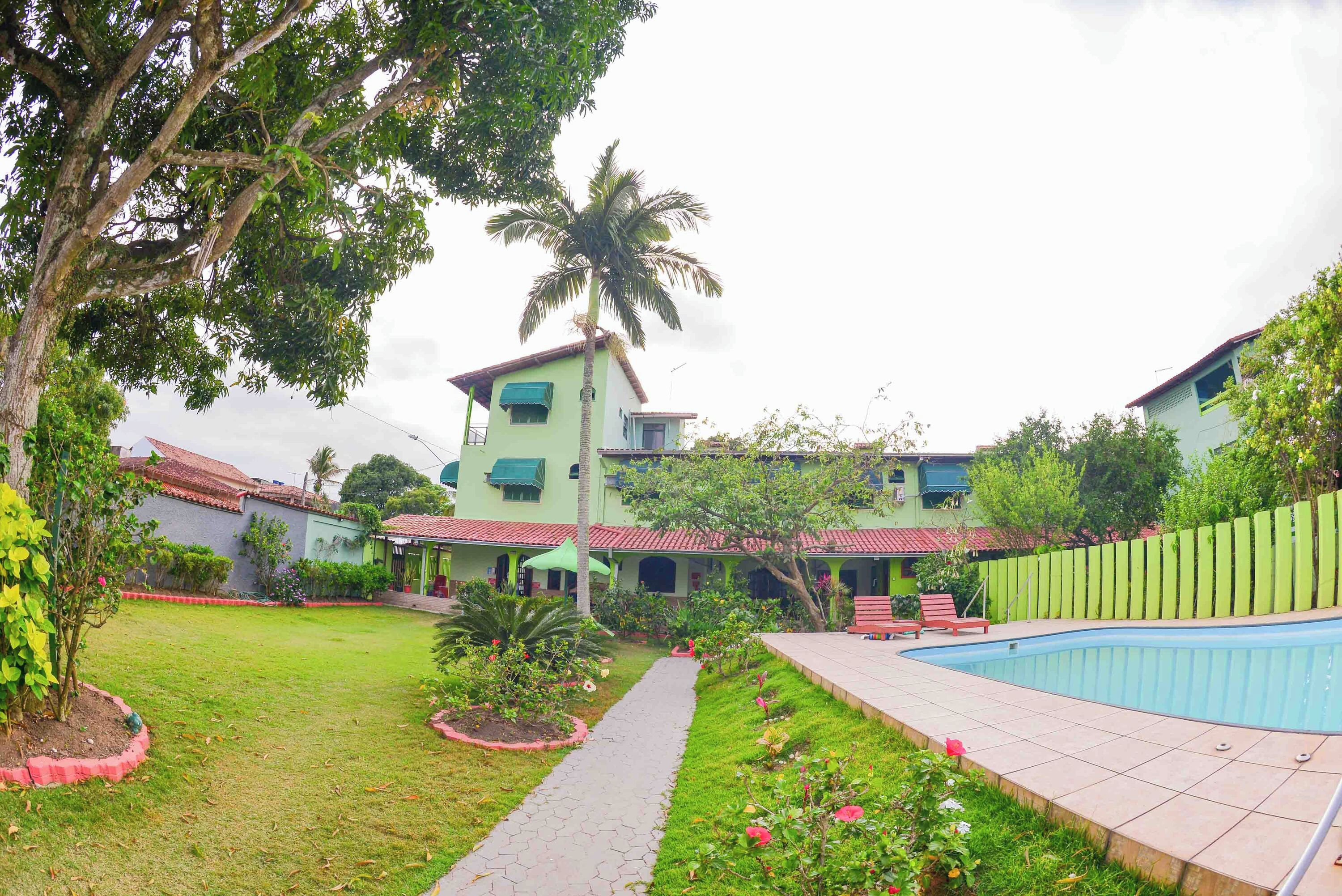 A residential property with a swimming pool, a garden, and a two-story building with a red-tiled roof.