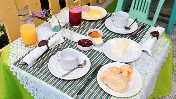 Une table mise pour le petit-déjeuner, avec des assiettes remplies de nourriture, un verre de jus et une tasse de café.