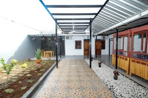 Un espacio exterior cubierto con suelo de baldosas, plantas en macetas y una zona de estar.