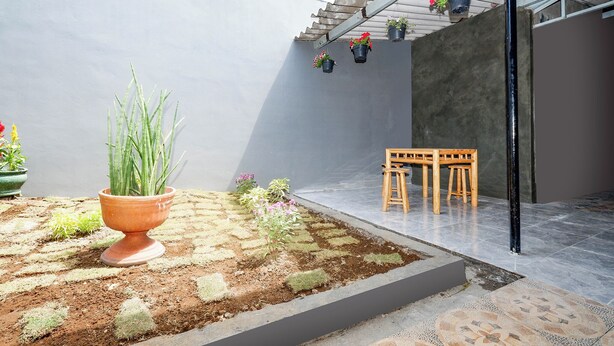 A courtyard with a potted plant, a wooden bench, and hanging flower pots. - Perdana Kasih Hotel Klaten by Zuzu (Klaten)