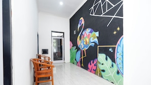A room with a black wall mural, a wooden chair, and a door leading to another room. - Perdana Kasih Hotel Klaten by Zuzu (Klaten)