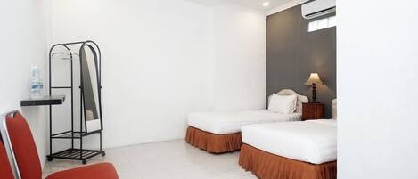 A hotel room with two beds, a desk, a chair, and a water bottle.