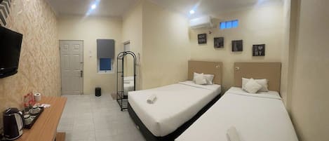 A hotel room with two beds, a desk with a coffee maker, a TV, and a door.