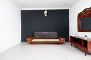 Une pièce avec un mur de couleur sombre, un canapé en bois avec un coussin, une petite table en bois et un miroir.