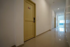 Ein Flur mit einer gelben Tür, einer weißen Wand und einem gefliesten Boden.
