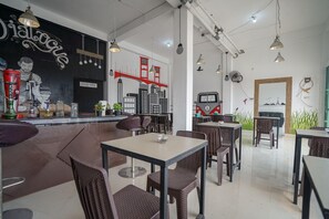 Un café moderno con mesas y sillas, una zona de bar y un mural con vistas a la ciudad.