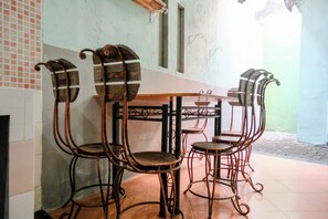 A dining area with a table and four chairs, a tiled floor, and a green wall. - Spot On 2046 Villa Hardi (Batu)