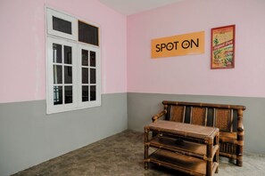 Quarto com janela, um banco de madeira e uma parede com o letreiro 'SPOT ON'.
