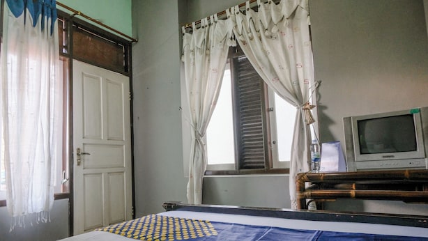 A room with a bed, a television, and a window with curtains. - Spot On 2046 Villa Hardi (Batu)