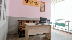 A room with a desk, a chair, a sign reading 'SPOT ON', and a poster on the wall. - Spot On 2046 Villa Hardi (Batu)