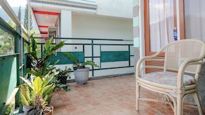 A balcony with potted plants, a wicker chair, and a door with a sign. - Spot On 2046 Villa Hardi (Batu)