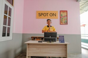 A reception desk with a 'SPOT ON' sign, a computer, and a poster on the wall. - Spot On 2046 Villa Hardi (Batu)