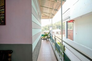 A corridor with a tiled floor, a metal railing, and a wall with a framed picture. - Spot On 2046 Villa Hardi (Batu)