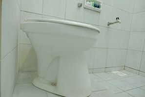 A white toilet in a bathroom with white tiles on the walls and floor. - Spot On 2046 Villa Hardi (Batu)