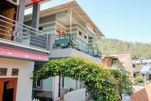 A multi-story building with a balcony, a white picket fence, and a lush green vine. - Spot On 2046 Villa Hardi (Batu)