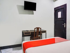 A room with a bed, a desk, a chair, a television mounted on the wall, and a door with a notice. - Ht O Makassar Near Mall Panakukkang (Makassar)