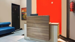 A reception desk with a modern design, a blue couch, and a fire extinguisher on the wall. - Ht O Makassar Near Mall Panakukkang (Makassar)