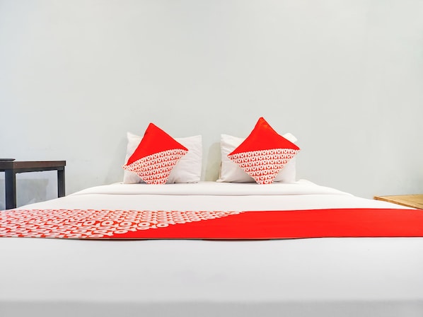 A neatly made bed with white bedding and two red pillows with white text. - Ht O Makassar Near Mall Panakukkang (Makassar)