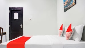 A bed with white and red bedding, a black door, and a small table. - Ht O Makassar Near Mall Panakukkang (Makassar)