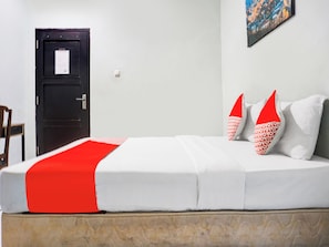 A bed with white and red bedding, a black door, and a small table. - Ht O Makassar Near Mall Panakukkang (Makassar)