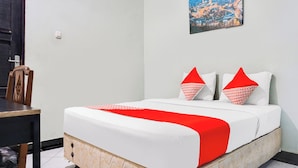 A hotel room with a bed, a painting on the wall, and a dining area with chairs. - Ht O Makassar Near Mall Panakukkang (Makassar)