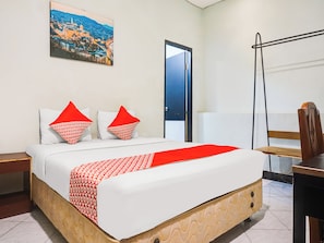 A hotel room with a bed, a nightstand, a desk, a chair, a door, and a wall-mounted picture. - Ht O Makassar Near Mall Panakukkang (Makassar)