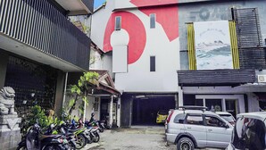 A building with a large red and white logo, a garage entrance, and several parked motorcycles. - Ht O Makassar Near Mall Panakukkang (Makassar)