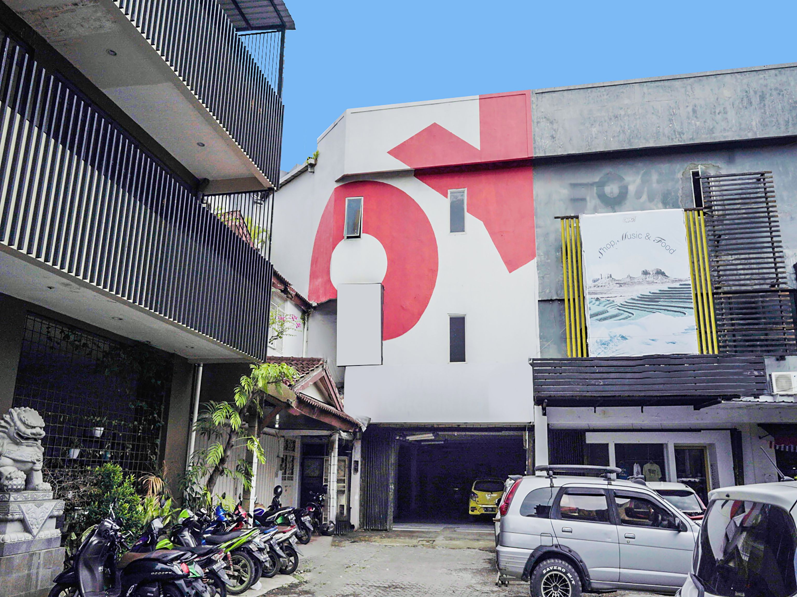 Un bâtiment orné d’un grand logo rouge et blanc, avec une entrée de garage et plusieurs motos garées devant.