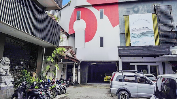 A building with a large red and white logo, a garage entrance, and several parked motorcycles. - Ht O Makassar Near Mall Panakukkang (Makassar)