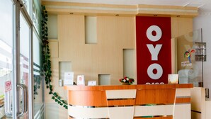 Un mostrador de recepción con detalles de madera y un letrero vertical rojo que dice "OYO".