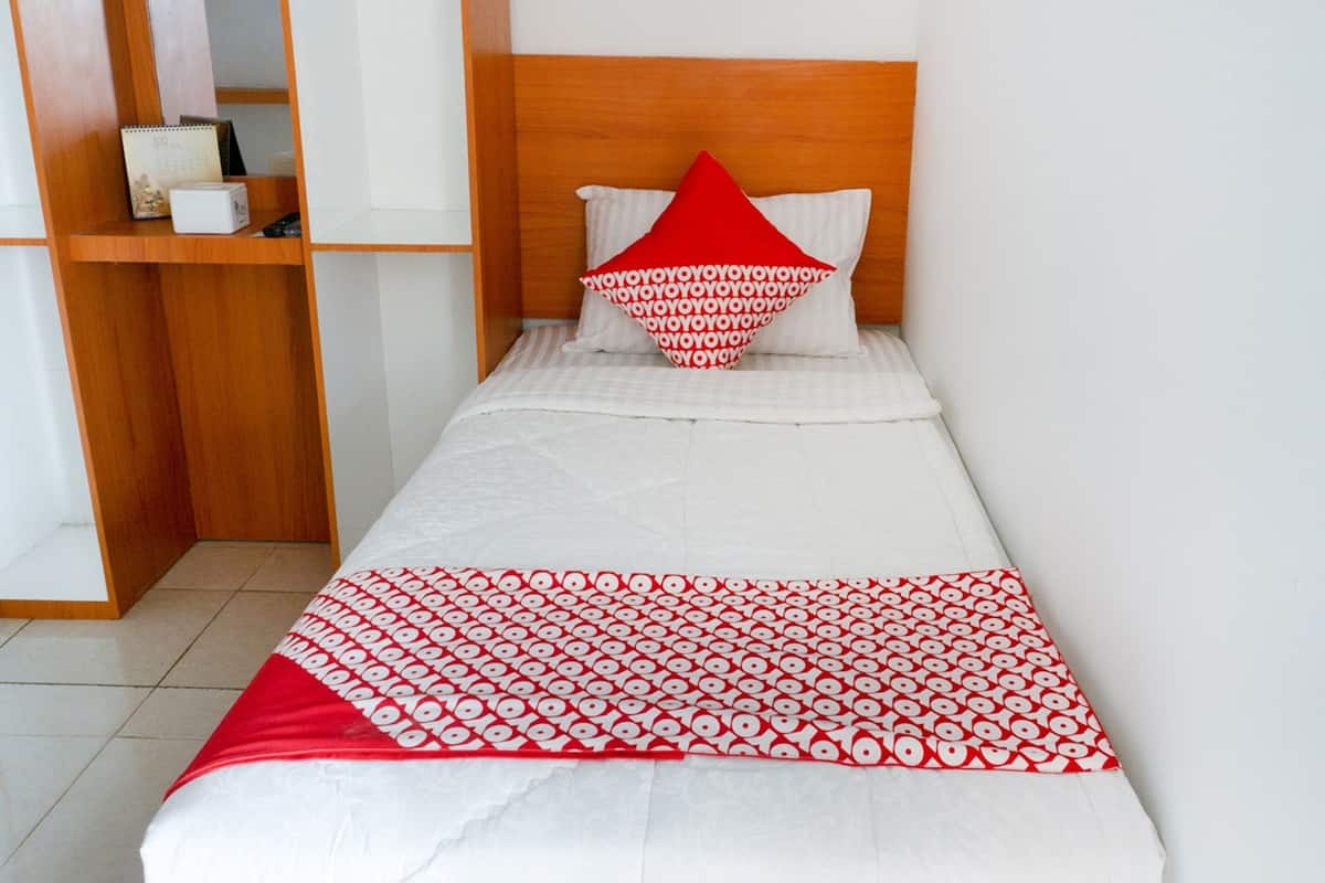 A neatly made bed with a red and white patterned bedspread, a wooden headboard, and a shelf with a calendar and a small box.
