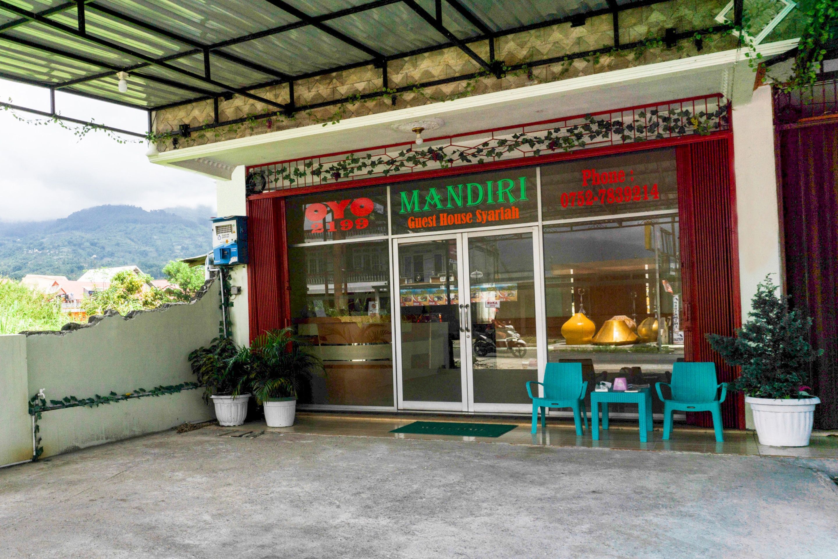 A guest house with a red entrance, a covered patio area with chairs, and potted plants.